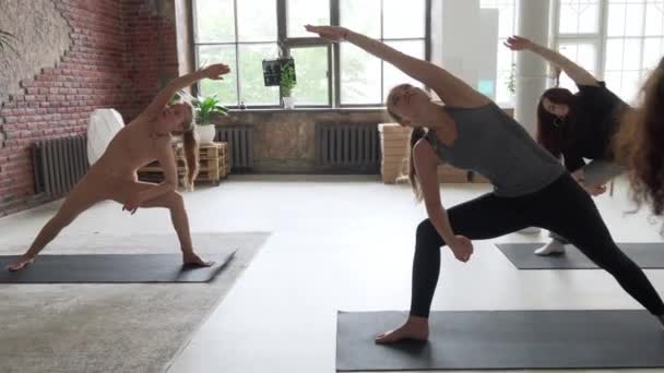 Jóvenes atractivas hembras haciendo yoga en gran estudio con instructor — Vídeos de Stock