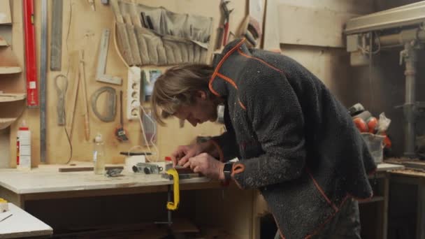Joven apuesto carpintero hacer afilar su herramienta en taller — Vídeos de Stock
