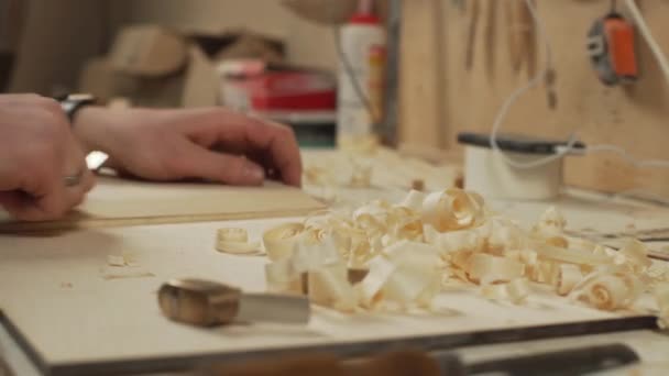 Fokus pada serutan: joiner mengakhiri pekerjaannya dengan sepotong kayu di bengkel — Stok Video