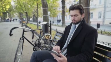 işadamı Bisiklet yakınındaki bir bankta oturmuş tablet kullanma