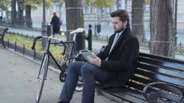 işadamı Bisiklet yakınındaki bir bankta oturmuş tablet kullanma