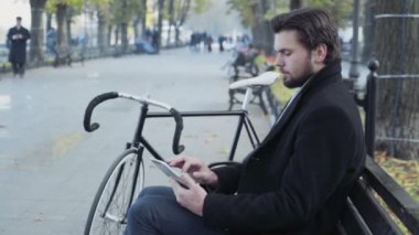 işadamı Bisiklet yakınındaki bir bankta oturmuş tablet kullanma