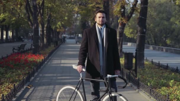 Giovane uomo d'affari in piedi con la bicicletta e guardare nella fotocamera — Video Stock