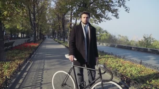 Ung affärsman stående på en stad gränd med cykel — Stockvideo