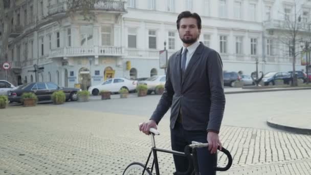Студент университета, стоящий на улице со своим велосипедом — стоковое видео