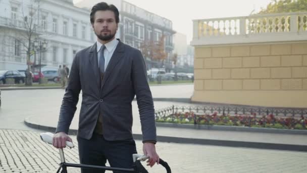 Étudiant mâle universitaire debout dans la rue avec son vélo — Video