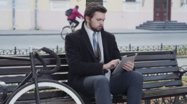 işadamı Bisiklet yakınındaki bir bankta oturmuş tablet kullanma