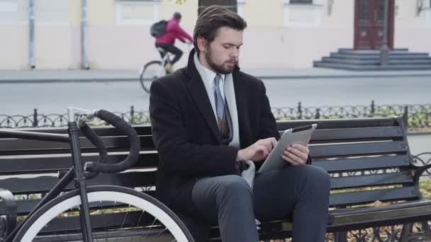 podnikatel pomocí tablet sedí na lavičce poblíž kolo