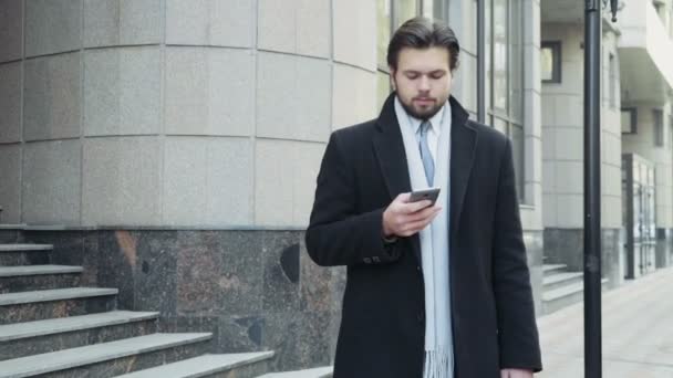 Hombre de negocios guapo usando un teléfono inteligente en el centro de — Vídeo de stock