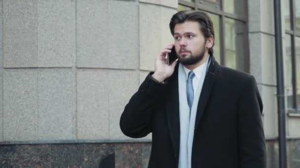 Hombre de negocios guapo terminando una llamada telefónica en el centro de la ciudad — Vídeo de stock