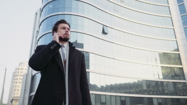 Hombre de negocios guapo hablando por teléfono en el centro de la ciudad — Vídeo de stock