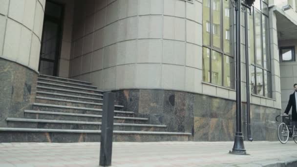 Hombre de negocios guapo caminando con su bicicleta en el centro de la ciudad — Vídeos de Stock