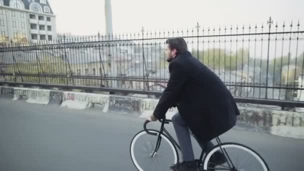 Guapo hombre de negocios montando una bicicleta en el centro de cámara lenta — Vídeo de stock
