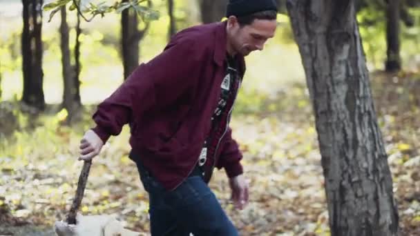 Giovane che gioca con due cani nel parco autunnale — Video Stock