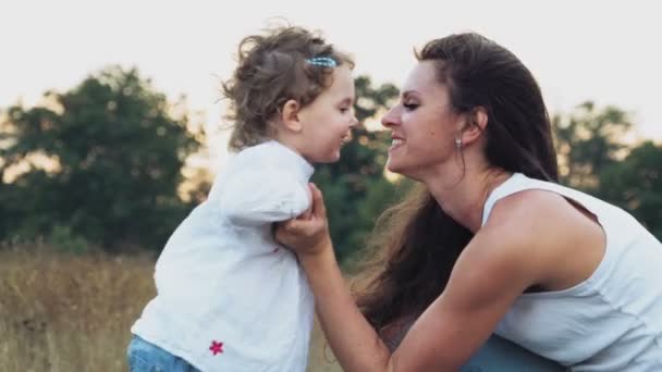 Мать целует свою маленькую милую дочь на открытом воздухе — стоковое видео