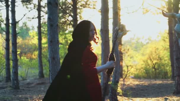 femelle rousse habillée en sorcière marchant, se retournant dans la forêt 