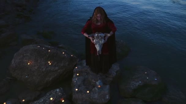 Mladá žena, oblečená jako čarodějnice drží býčí lebka — Stock video