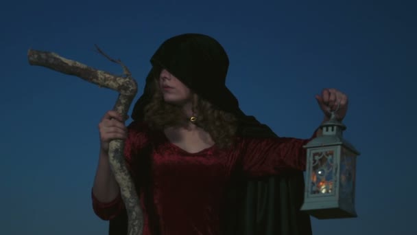 Young female dressed as a witch posing with a stick and lamp — Stock Video