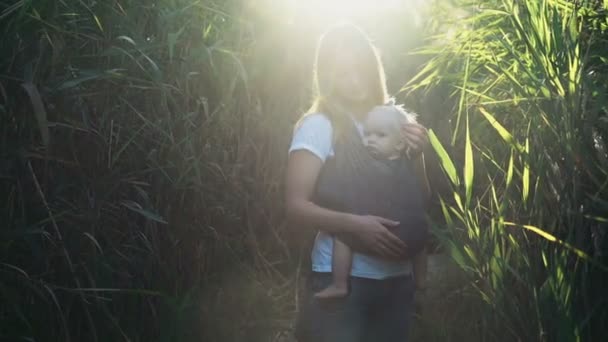 Portage de bébé, jeune femelle porter un bébé en fronde — Video