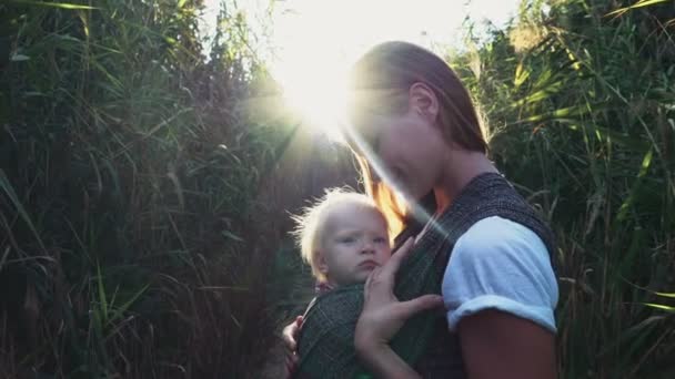 Ropa de bebé, madre con un bebé en cabestrillo — Vídeo de stock