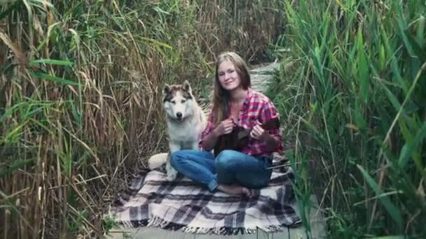 Jovem fêmea jogar no ukulele com um cão husky — Vídeo de Stock