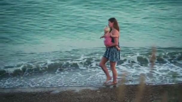 mère tenant bébé fille marchant sur la plage 