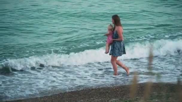 Modern som håller baby flicka promenerar på stranden — Stockvideo