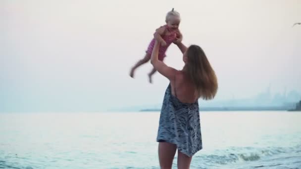 Moeder met een meisje van de baby in armen spatten van de zee-Golf — Stockvideo