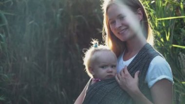 Babywearing, arkadan kovalayan bir bebek taşıyan anne
