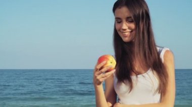 bir elma ile denizin arka planda tutan genç erkek gülümseyen