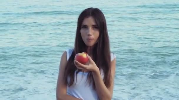 Jeune femme manger une pomme sur la plage — Video