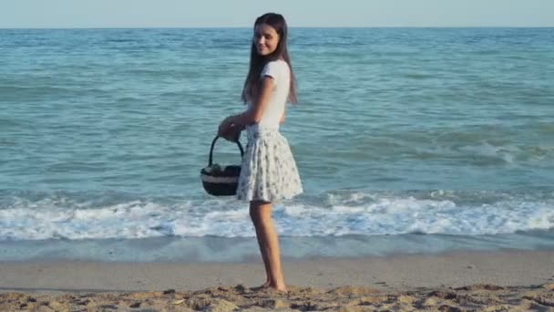 Девушка с корзиной фруктов, гуляющая у моря — стоковое видео