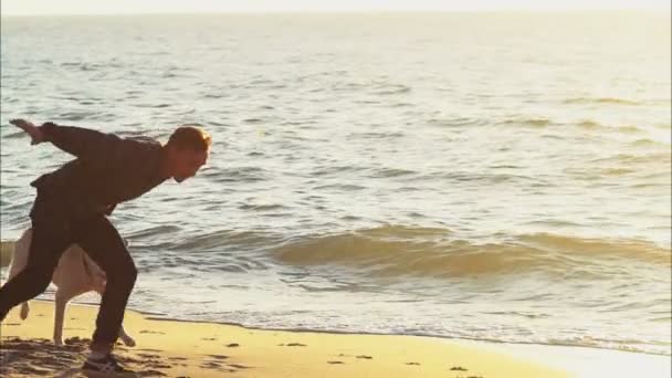 Jovem brincando com um cão na praia câmera lenta — Vídeo de Stock