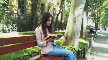 genç kadın parkta bankta bir kitap okuma