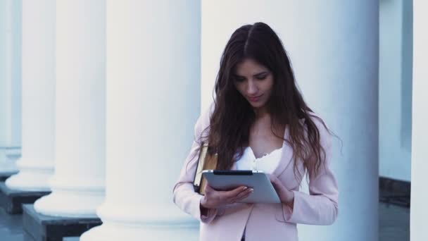 Estudiante bastante femenina usando una tableta en el campus — Vídeos de Stock