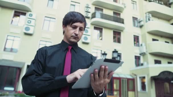 Schöner Geschäftsmann mit einem Tablet auf der Straße Zeitlupe — Stockvideo