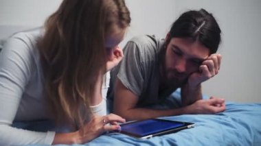 erkek ve kadın yatakta döşeme tablet kullanma