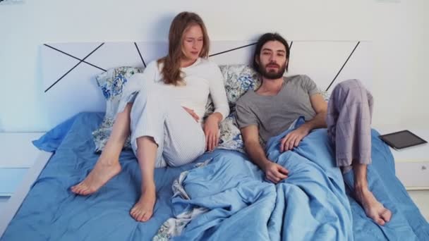 Смішний чоловік і жінка в ліжку дивиться на камеру — стокове відео