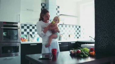bir bebek tutan ve onu bir elma mutfak at besleme genç anne