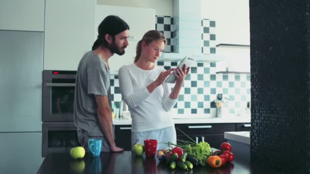 남자와 여 자가 부엌에서 아침 식사 중 태블릿을 사용 하 여 인터넷을 서핑 — 비디오
