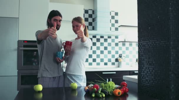 Jonge gelukkige paar staande op de keuken in de ochtend duimen opdagen — Stockvideo