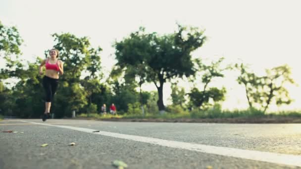 Corredor femenino y ciclista masculino en el sendero del parque cámara lenta — Vídeo de stock