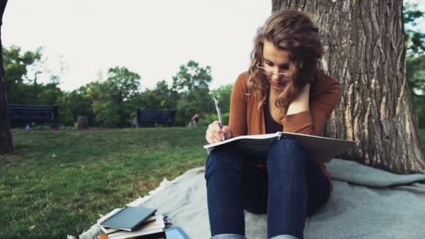 Vrouwelijke student met een notebook in park slow motion — Stockvideo