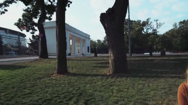 Портрет усміхненої студентки, що сидить під деревом у парку — стокове відео