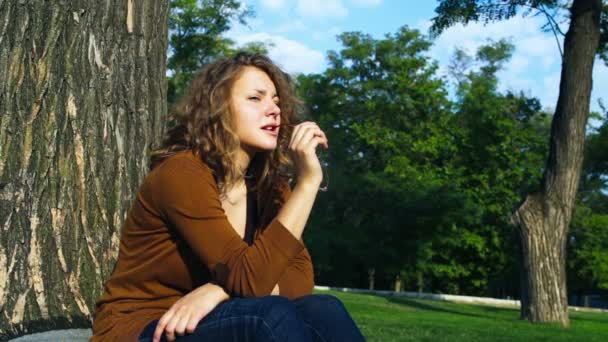 Tankeväckande kvinnlig student sitter under träd slow motion — Stockvideo