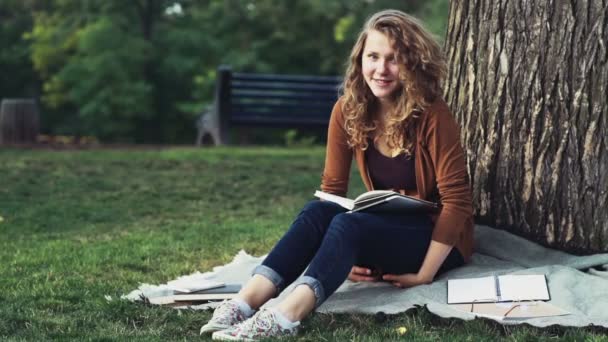 Portret van een gelukkig vrouwelijke student zitten in het park slow motion — Stockvideo