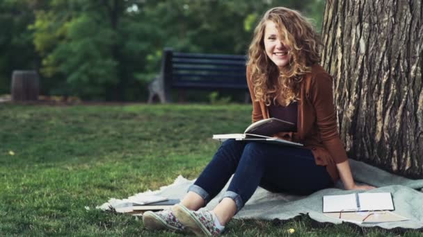 Портрет щасливої студентки, що сидить у парку повільний рух — стокове відео