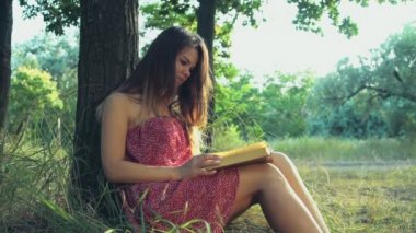genç kadın bir yaz günü ağır çekim ormandaki bir kitap okur
