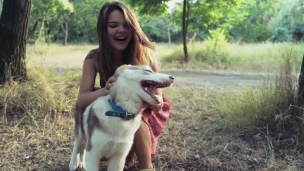 Teenage girl plays with a husky puppy in forest slow motion — Stock Video