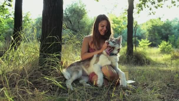 Молодая женщина дразнит хаски-собаку в лесу замедленной съемки — стоковое видео